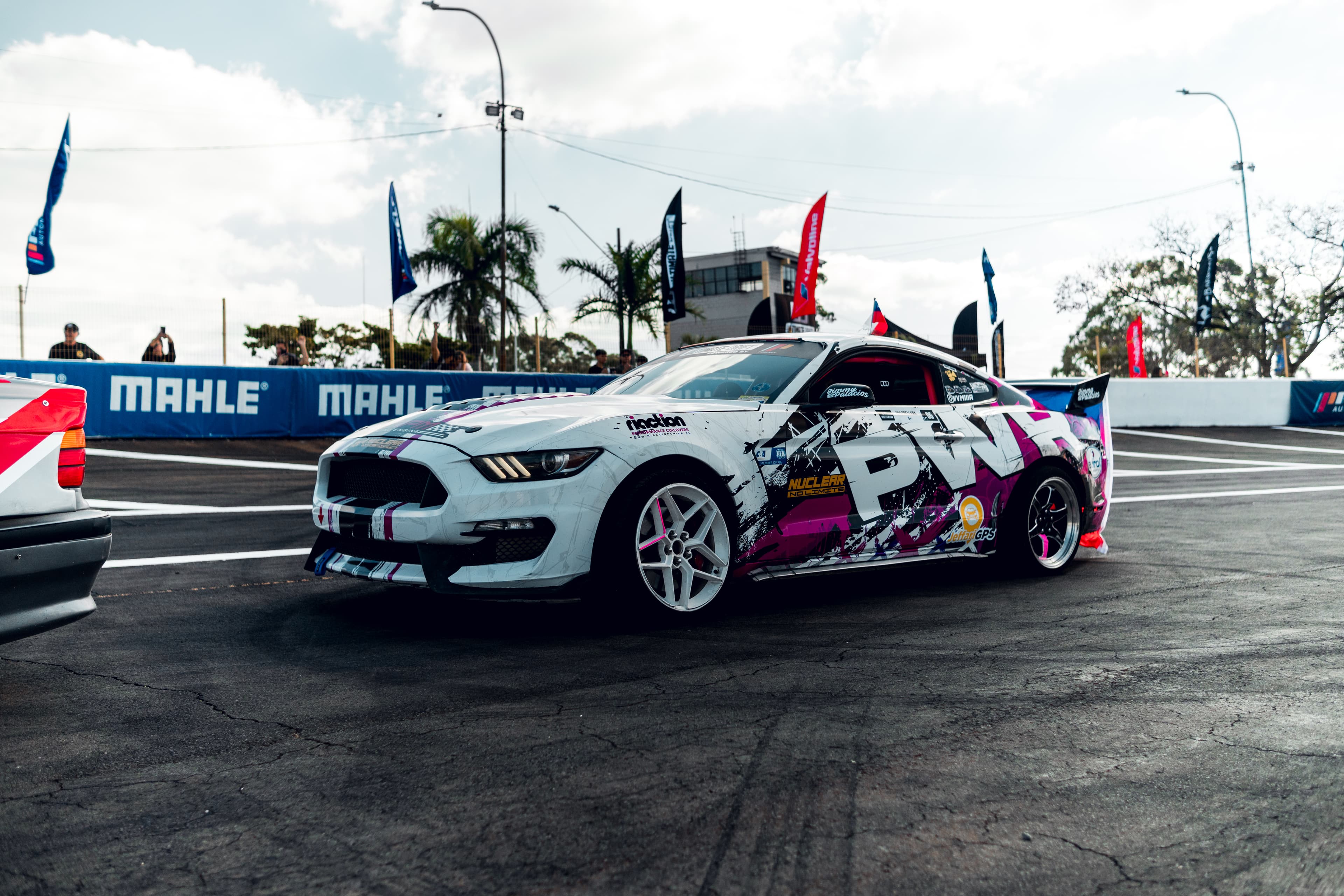 Mustang de competencia en la pista, banderas al fondo